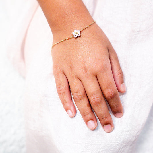 Hand wearing a delicate bracelet on a white background. Harma Jewelry Gold plated Little Bloom PINK Zirconia Bracelet