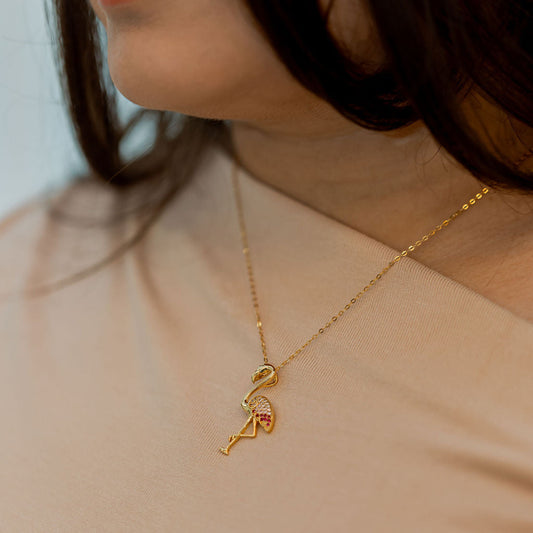 Close-up of a person wearing a gold necklace with a key pendant. I Am Becoming PINK Again Flamingo Necklace