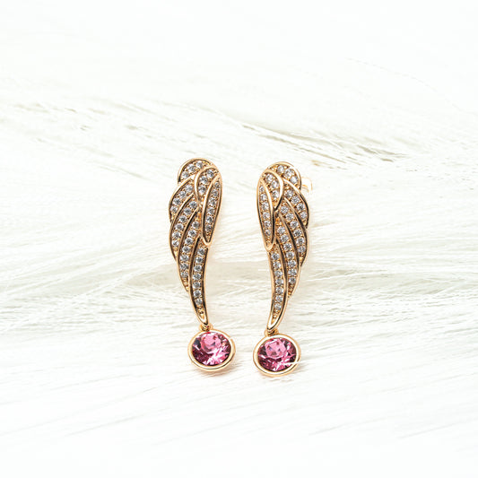 Gold wing-shaped earrings with pink gemstones on a white background. Harma gold plated Rise Again Crystal Wings Earrings