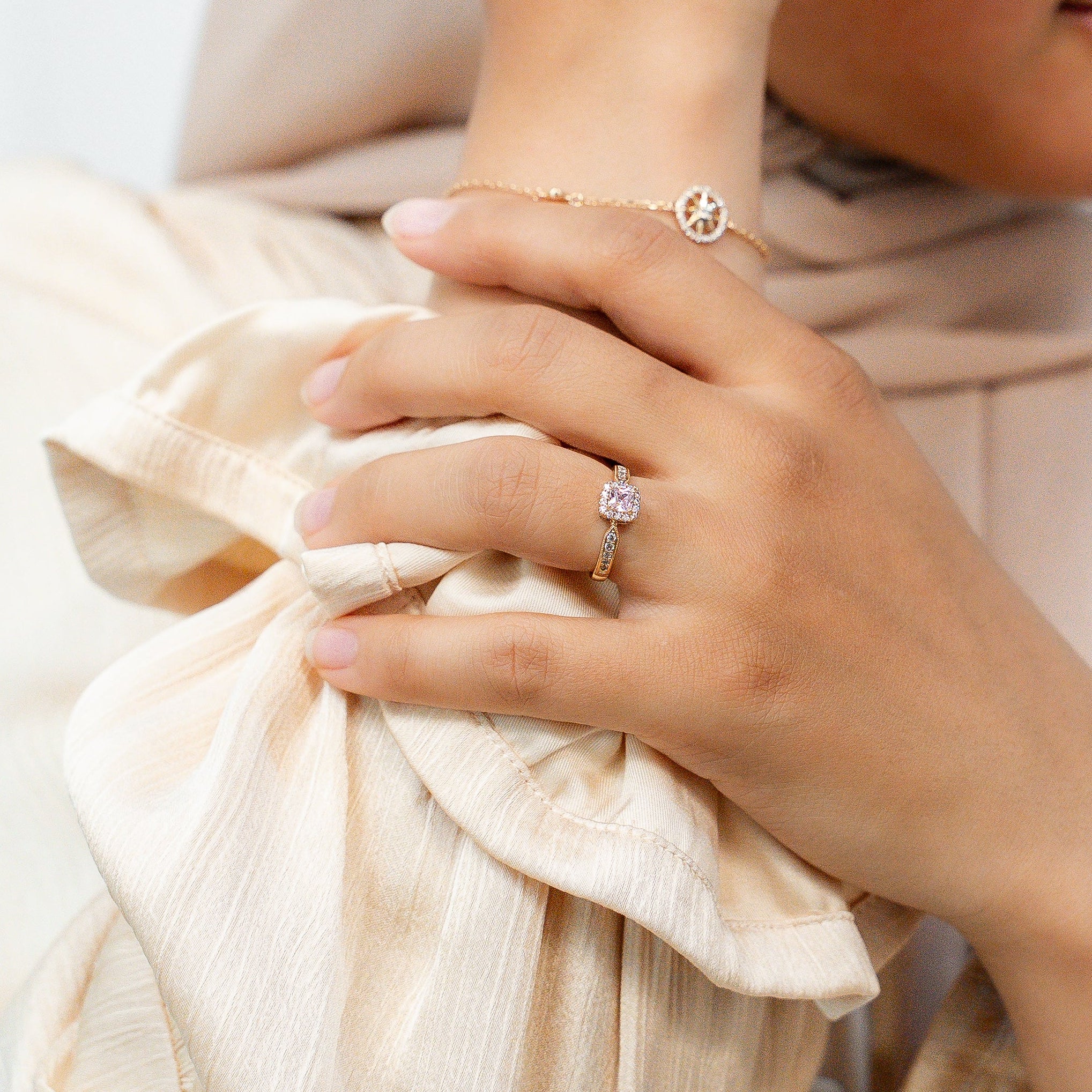 Woman wearing a beige hijab and jewelry against a white background