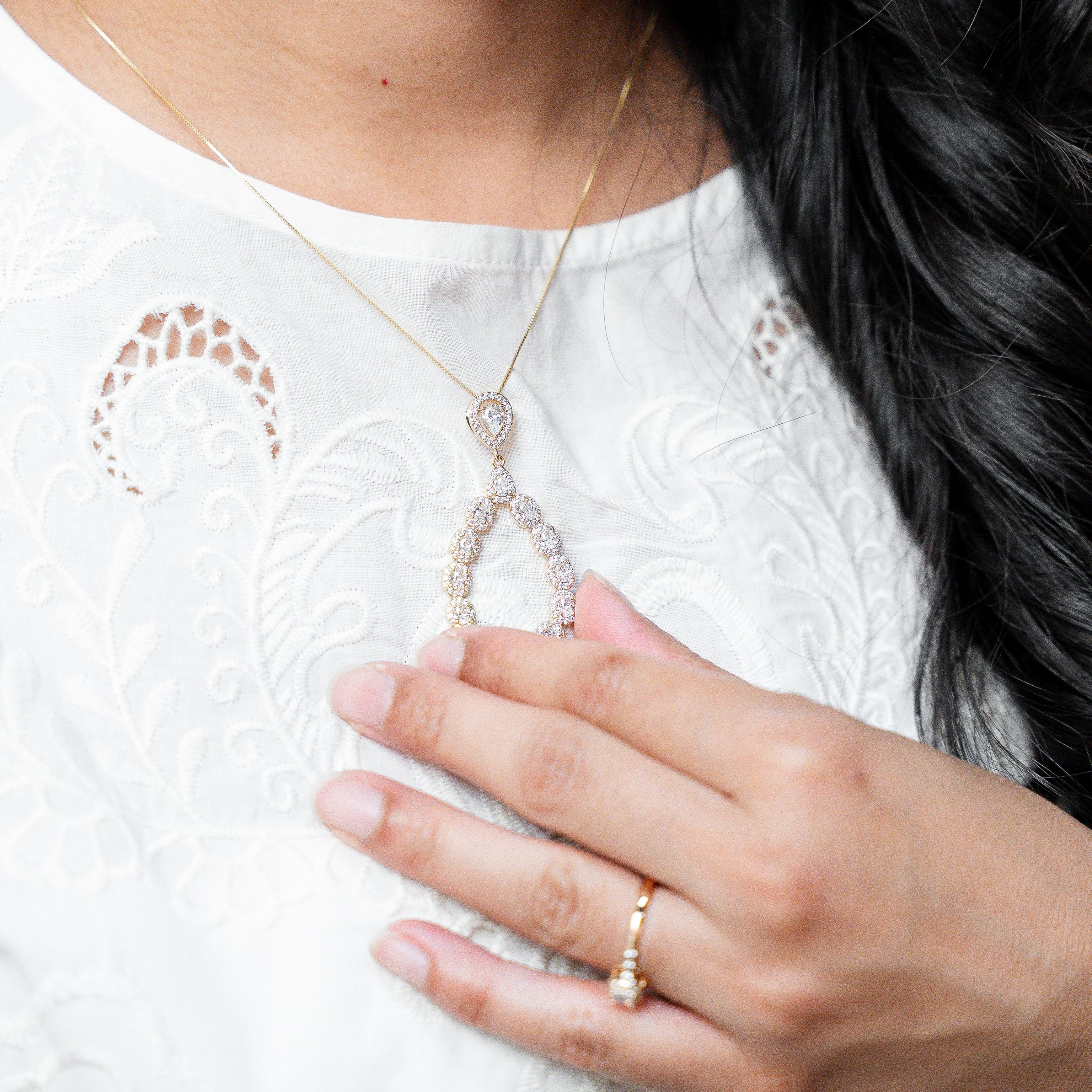 Person wearing a necklace and ring, with a focus on jewelry details.