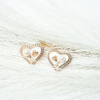 Heart-shaped earrings with pearl and gold details on a white fur background