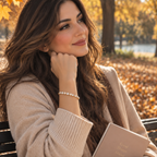 A woman sitting on a park bench in autumn, wearing a beige knit cardigan and holding a notebook, with a pearl bracelet visible on her wrist. Autumn Constellation Zirconia Bracelet | Harma Jewelry 18k gold plated