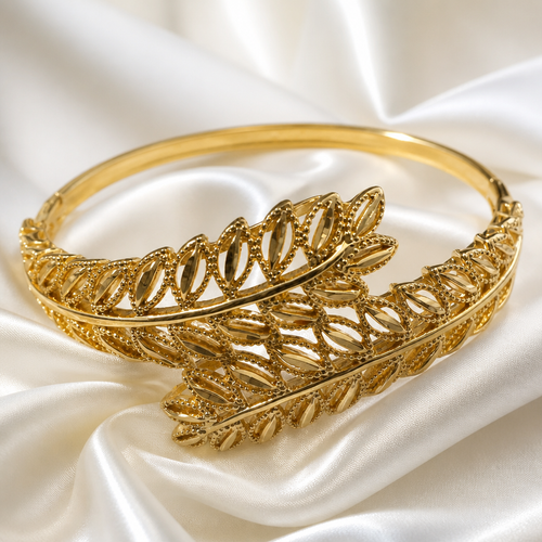 Gold bracelet with leaf design on a white satin background