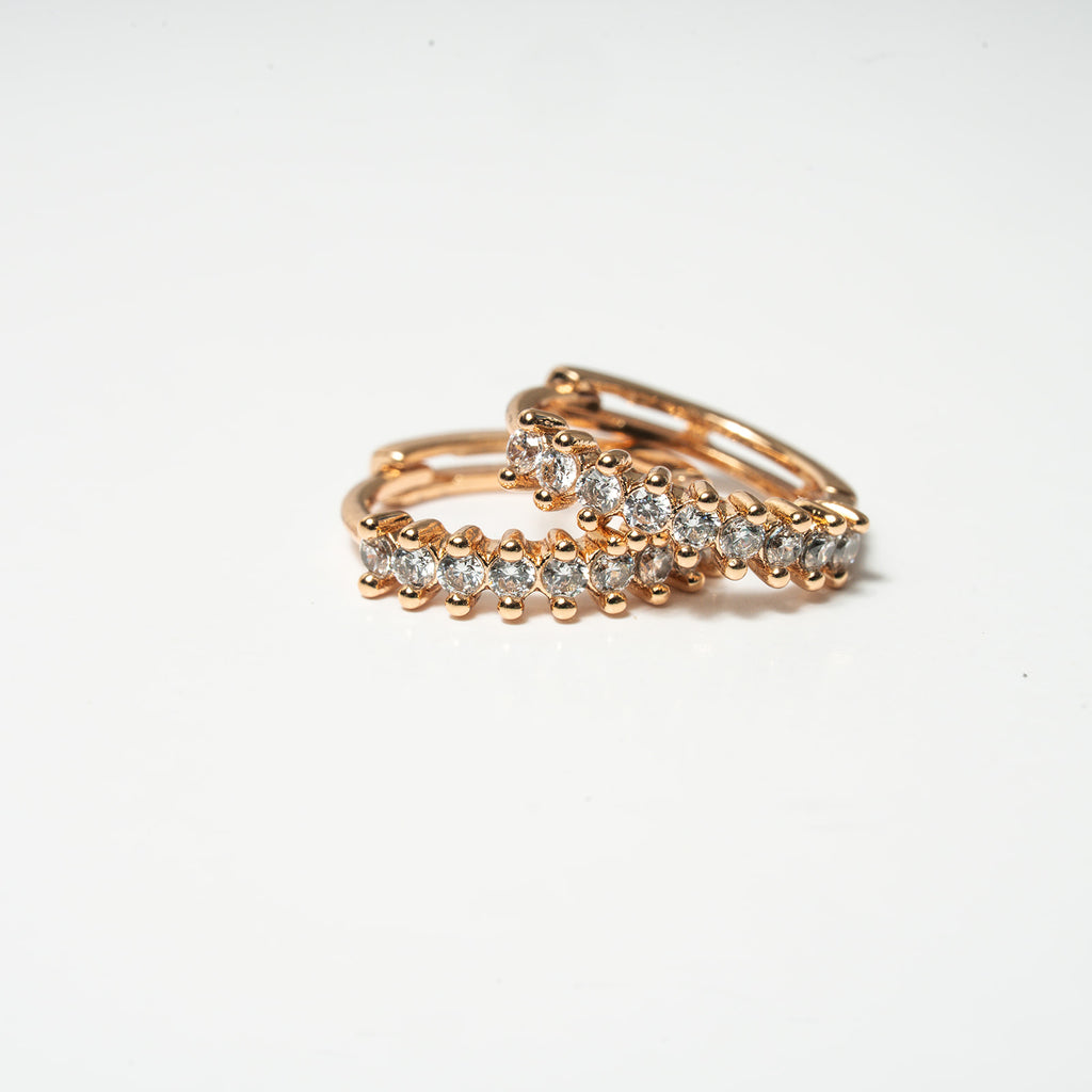 Rose gold ring with embedded diamonds on a light gray background Harma Aurora Glow Hoop Earrings