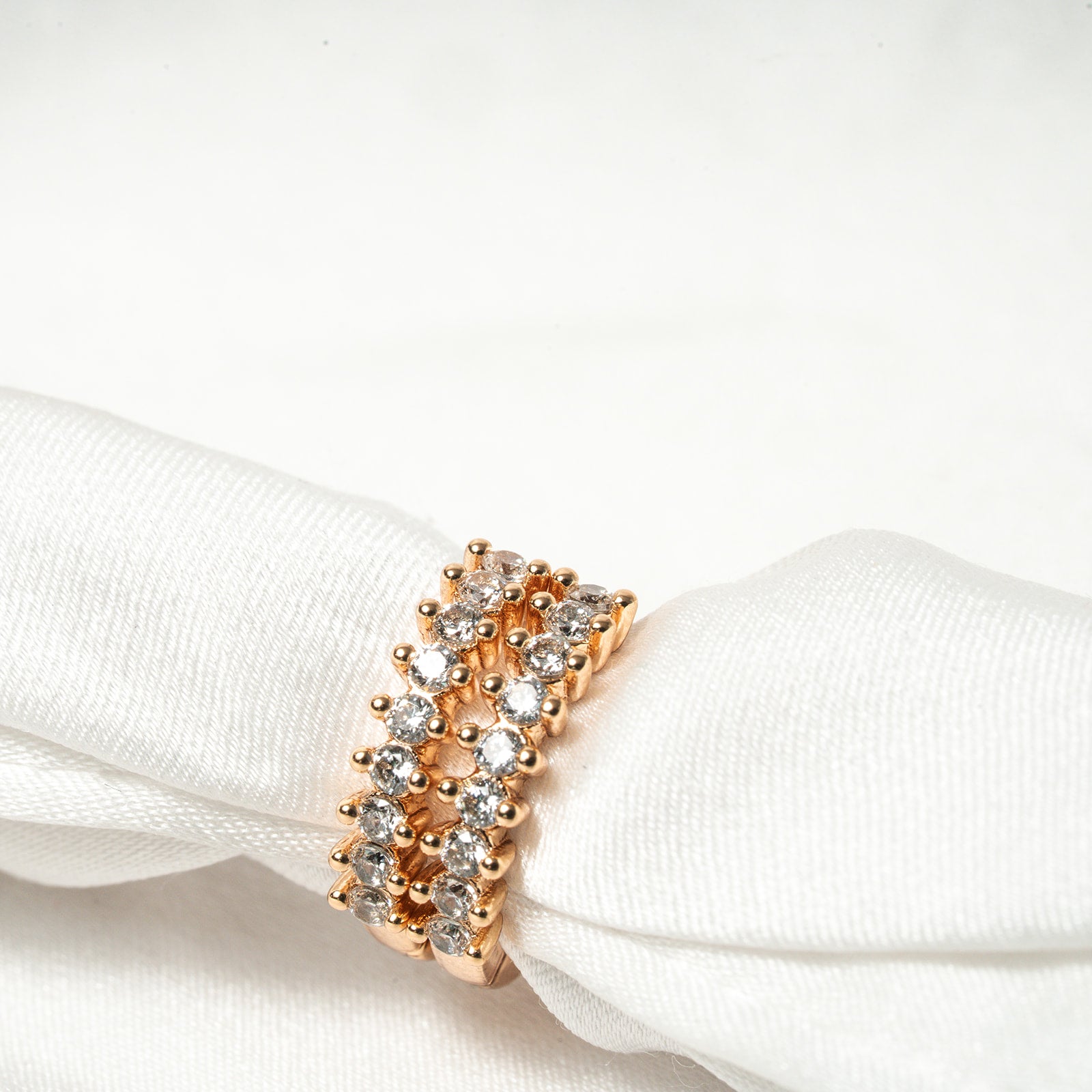 Rose gold ring with diamonds on a white fabric background Harma Aurora Glow Hoop Earrings