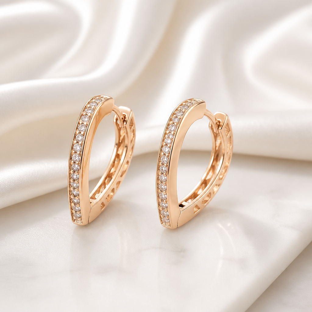 Rose gold hoop earrings with diamond accents on a soft white fabric background