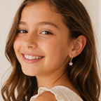 Young girl with a smile wearing a white top against a neutral background and pink floral hoop earrings 