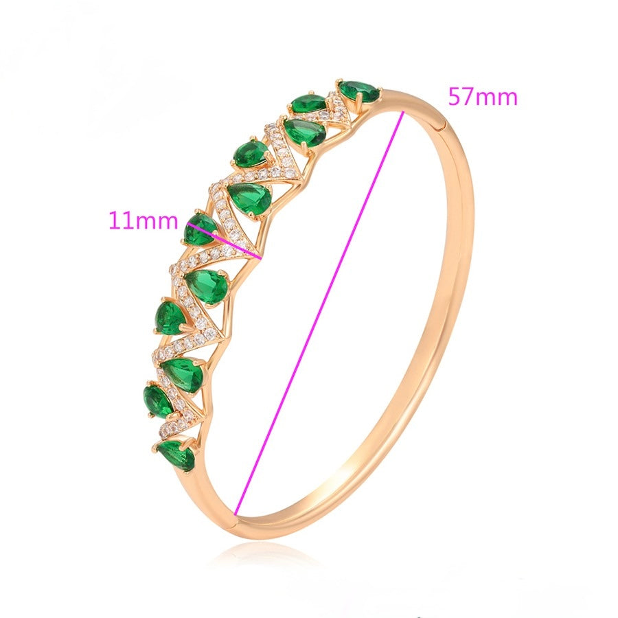 Gold bracelet with green gemstones and measurements on a white background