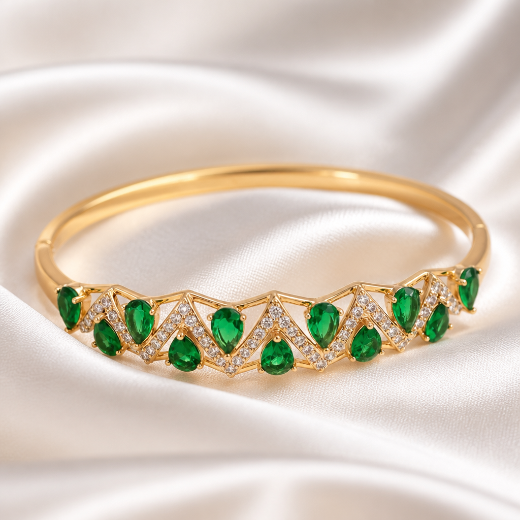 Gold bracelet with emerald green gemstones on a satin background