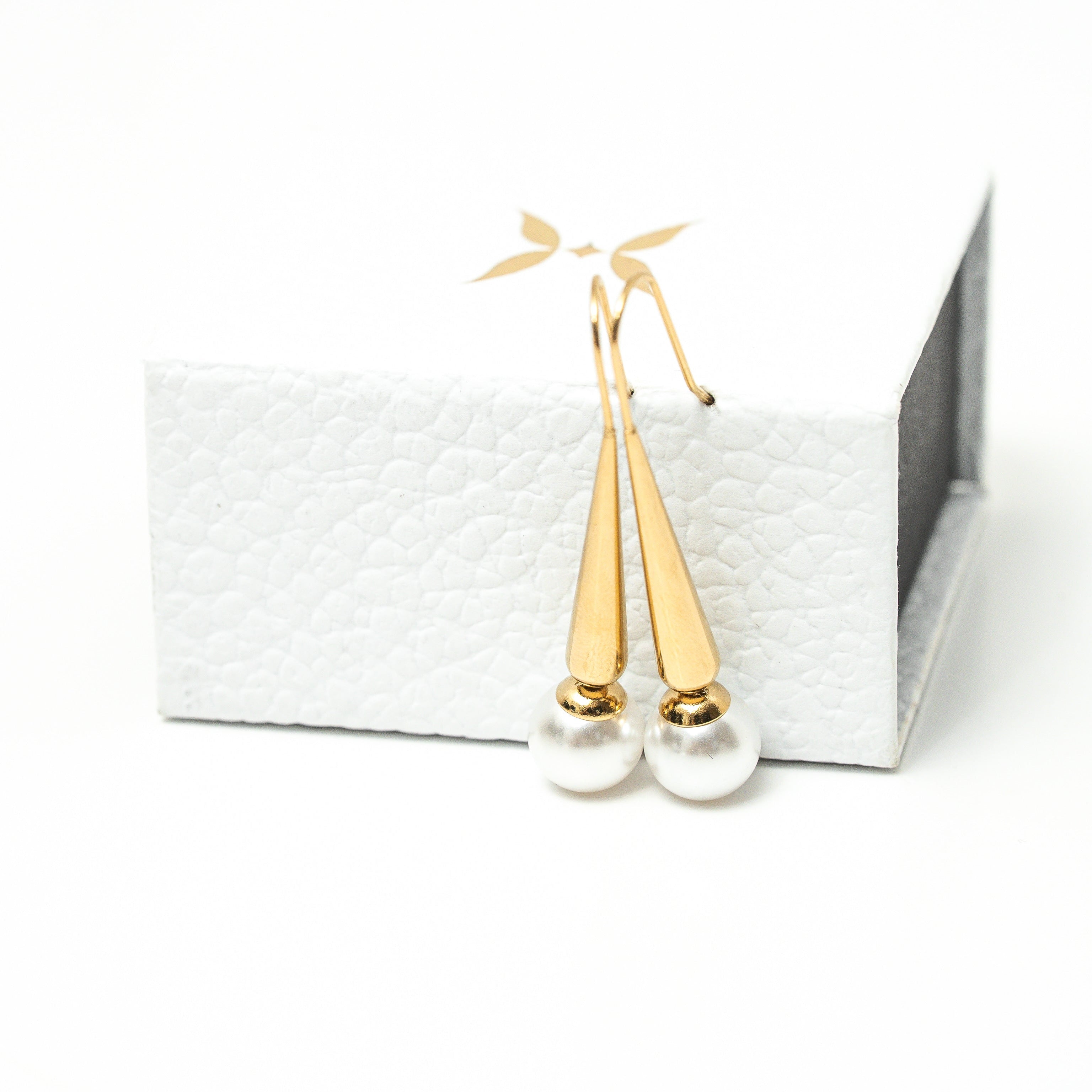 Gold earrings on a white card with a white background. Harma Gold Plated Pearl I Am Grounded Dangle Earrings
