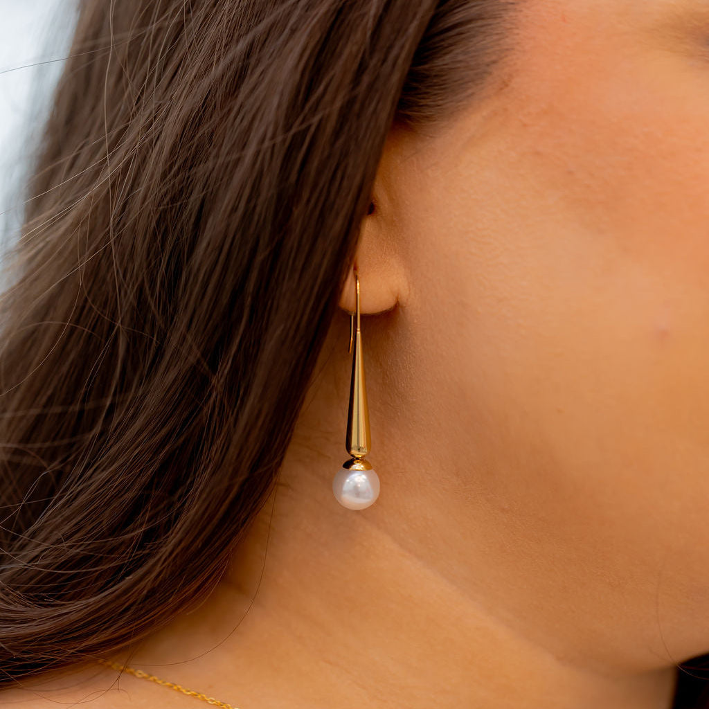 Close-up of a person wearing a gold earring with a pearl drop. Harma Gold Plated Pearl I Am Grounded Dangle Earrings