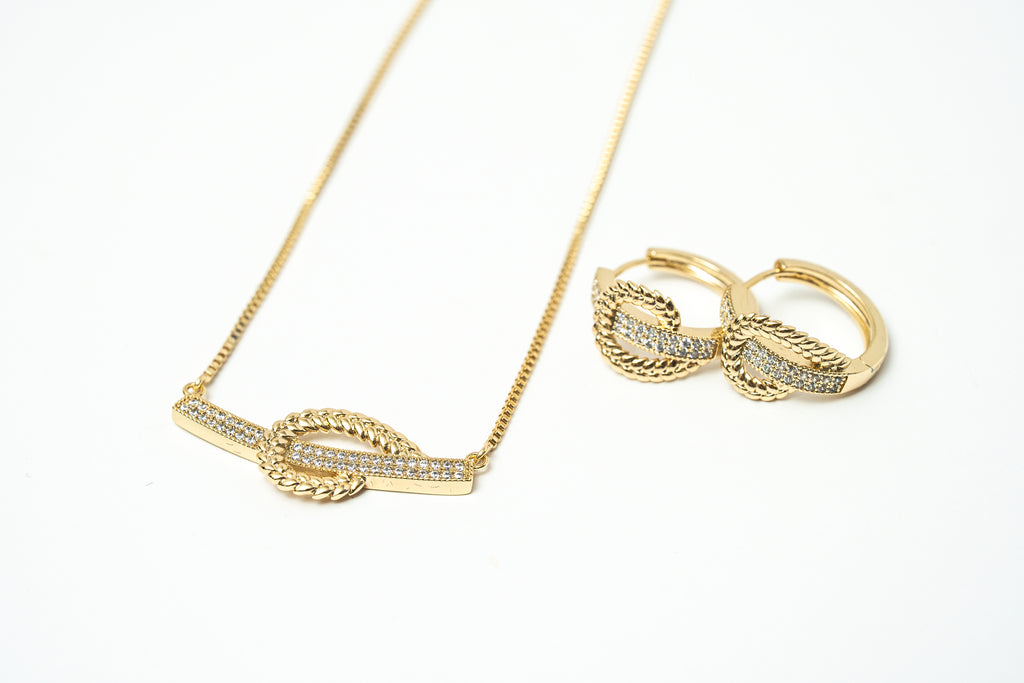 Gold necklace and earrings on a white background. Harma Gold plated I Am at Peace Vine Hoop Necklace 