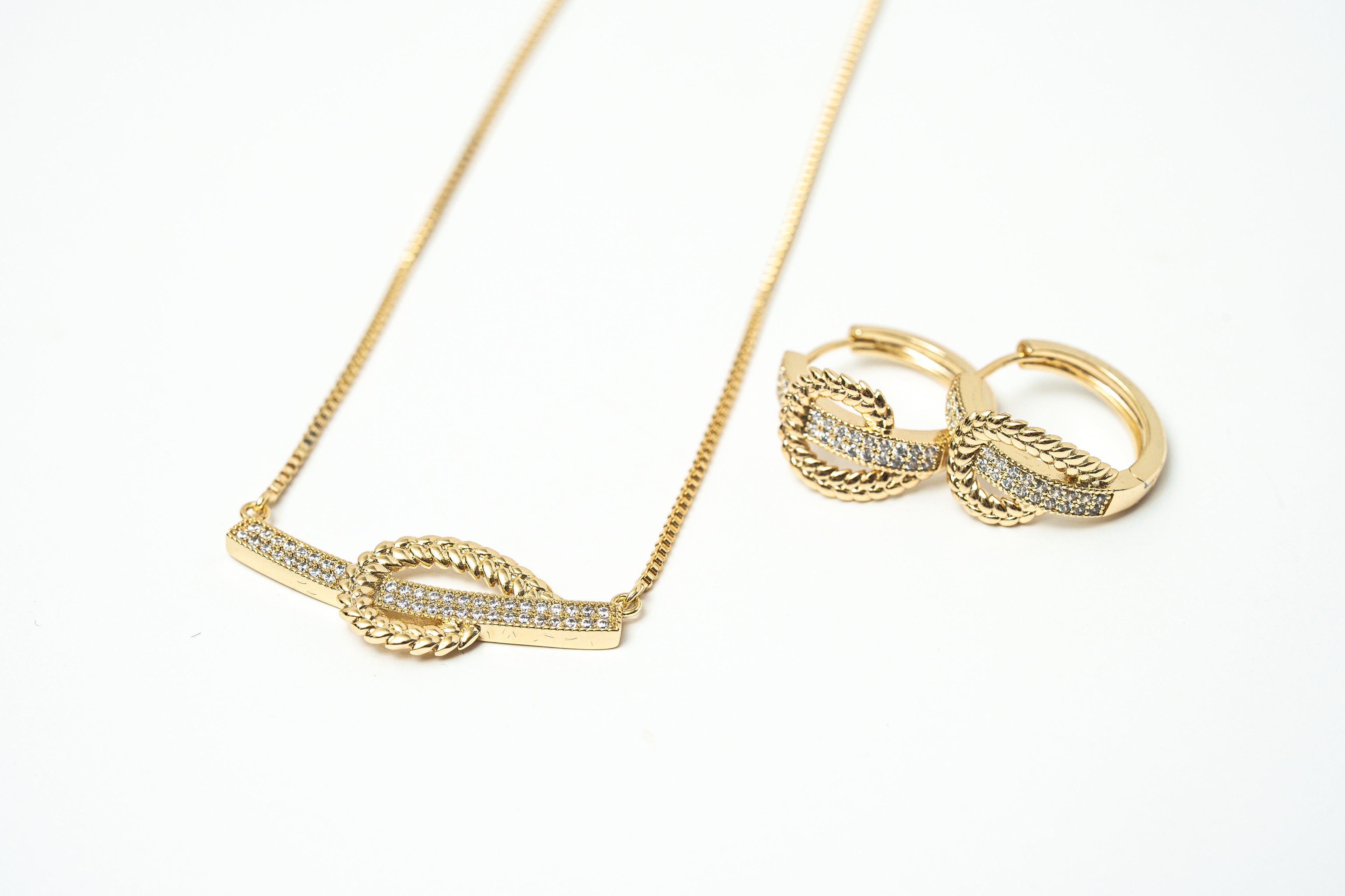 Gold necklace and earrings on a white background. Harma Gold plated I Am at Peace Vine Hoop Necklace 