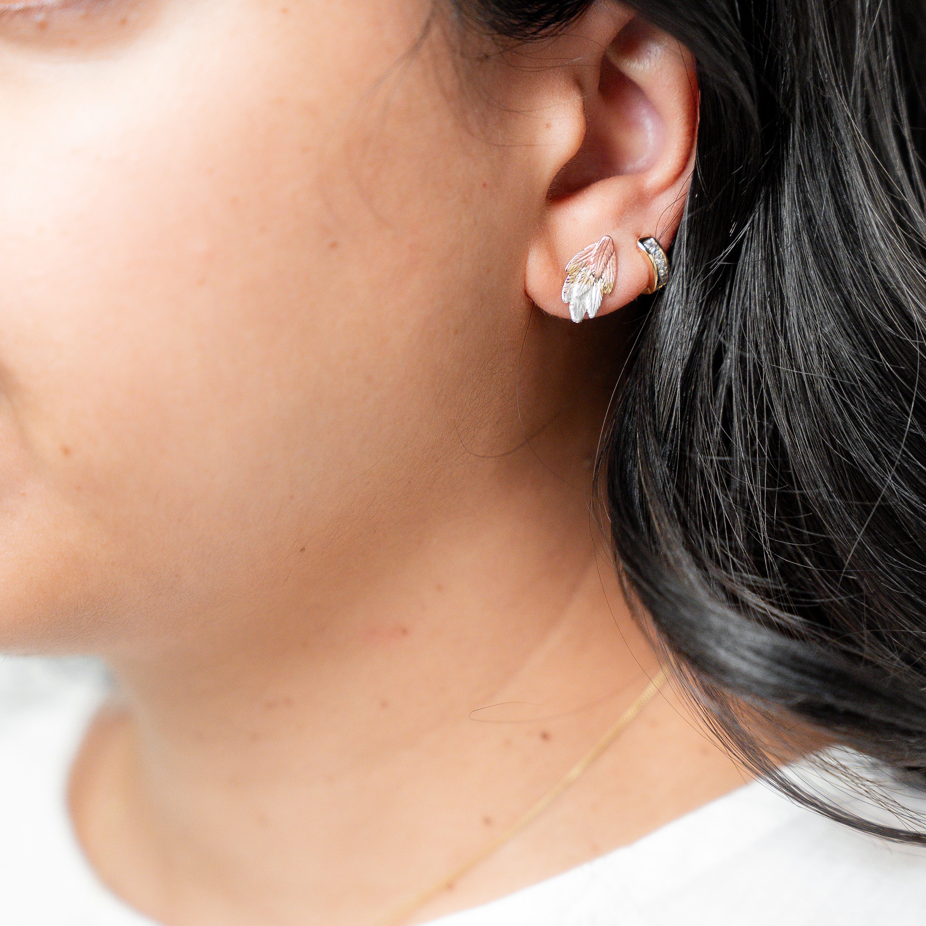 Close-up of a person wearing diamond earrings with a neutral background. Harma Gold plated I am Free Tri-tone Stud Earrings