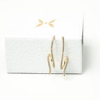 Gold hoop earrings on a white box with a white background. Harma Gold plated Rise in Flow Sparkle Earrings