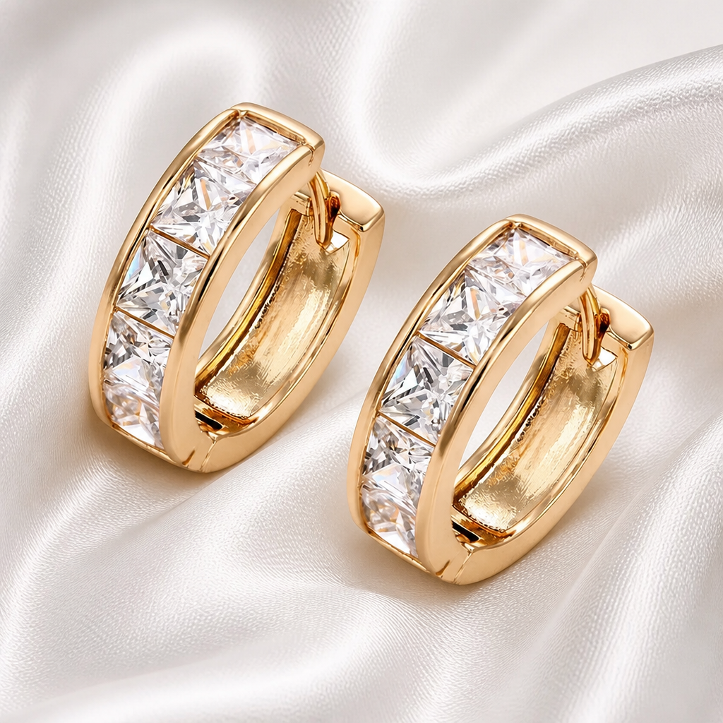 Gold hoop earrings with clear gemstones on a white satin background