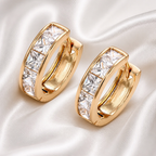 Gold hoop earrings with clear gemstones on a white satin background