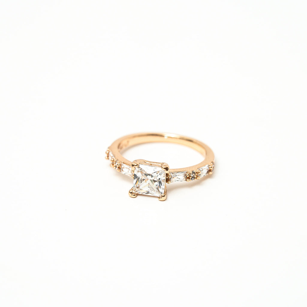 White princess cut stone with cubic zirconia around the ring in baguette cut with white background. solitair ring 