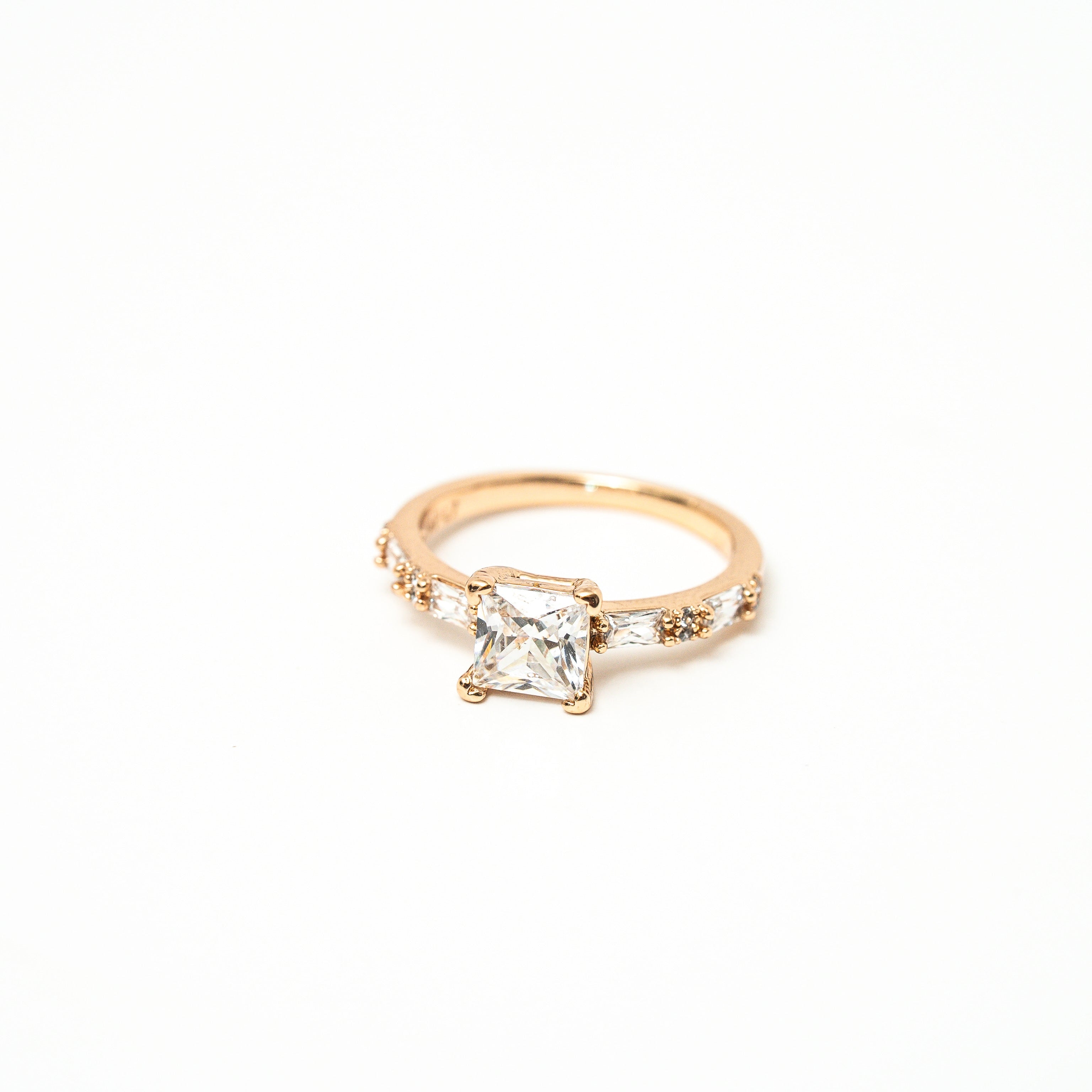White princess cut stone with cubic zirconia around the ring in baguette cut with white background. solitair ring 