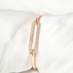 Rose gold bracelet with clear stones on a white cushion. Harma Jewelry Cubic Zirconia Incrusted Sumptuous Paper Clip Bangle Chain