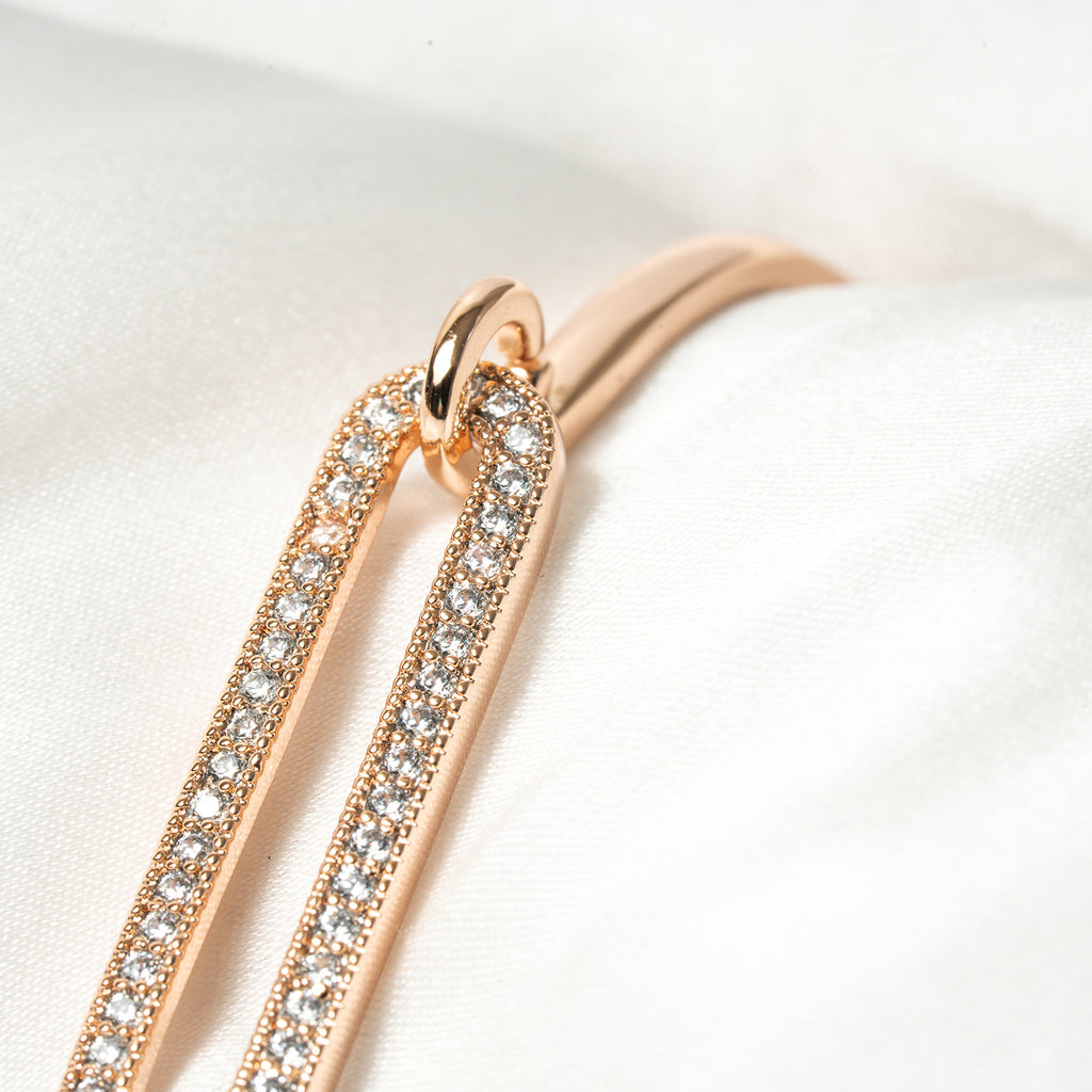 Rose gold hoop earrings with clear gemstones on a white background. Harma Jewelry Cubic Zirconia Incrusted Sumptuous Paper Clip Bangle Chain