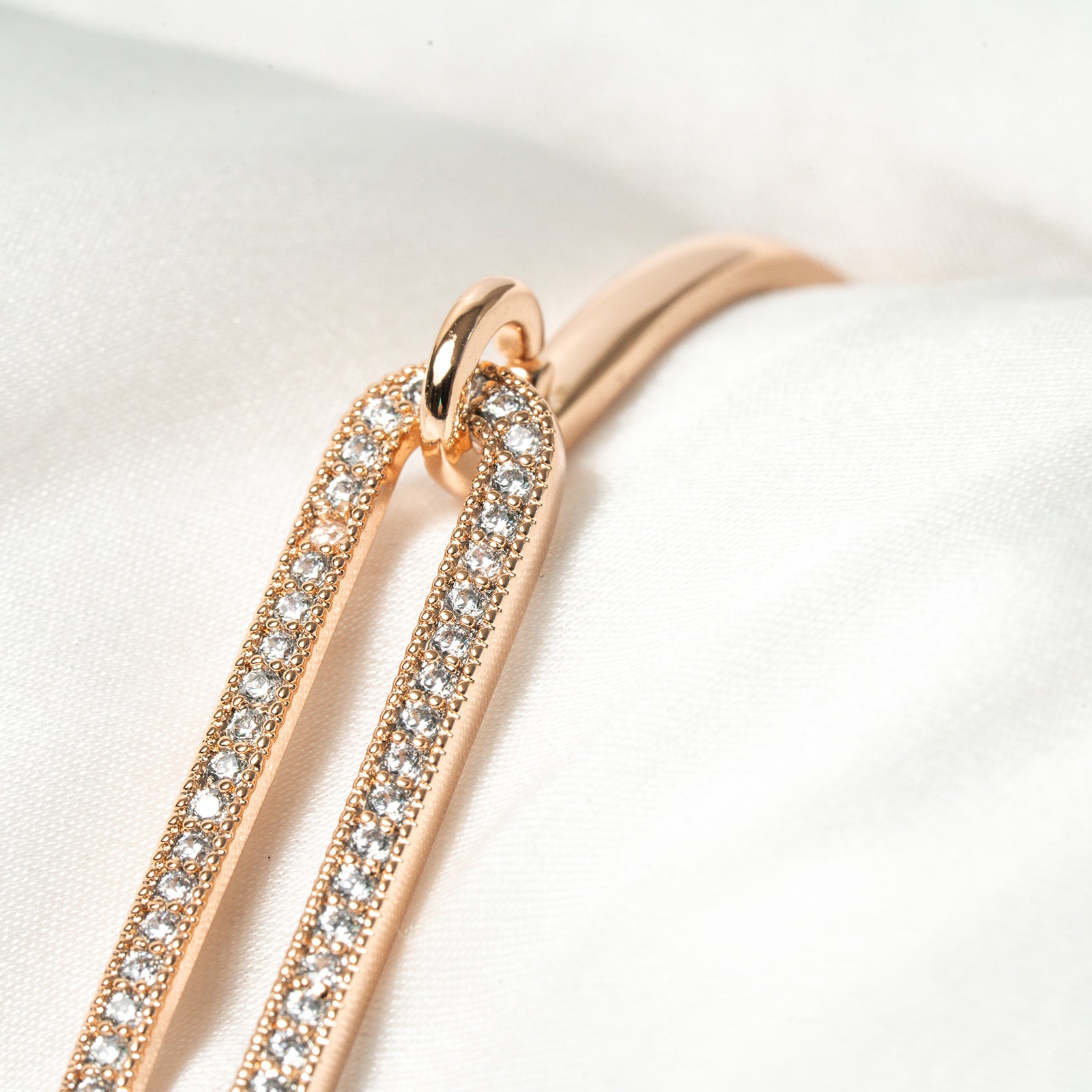 Rose gold hoop earrings with clear gemstones on a white background. Harma Jewelry Cubic Zirconia Incrusted Sumptuous Paper Clip Bangle Chain