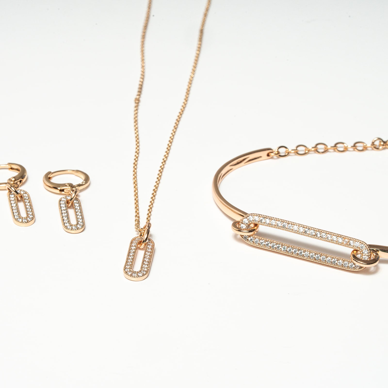 Rose gold jewelry set including necklace, bracelet, and earrings on a white background. Harma Jewelry Cubic Zirconia Incrusted Sumptuous Paper Clip Bangle Chain Necklace Earrings Set
