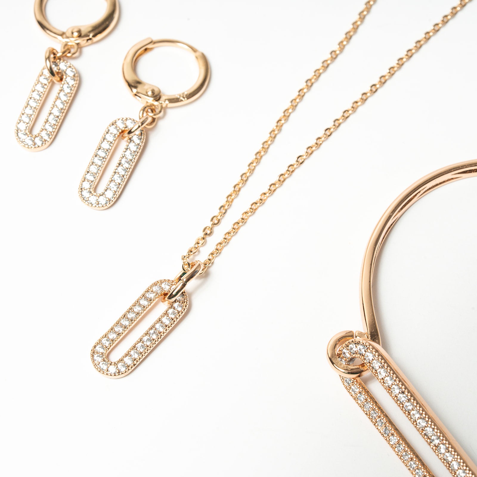 Rose gold jewelry set including necklace, hoop earrings, and bracelet on a white background. Harma Jewelry Cubic Zirconia Incrusted Sumptuous Paper Clip Bangle Chain Necklace Earrings Set