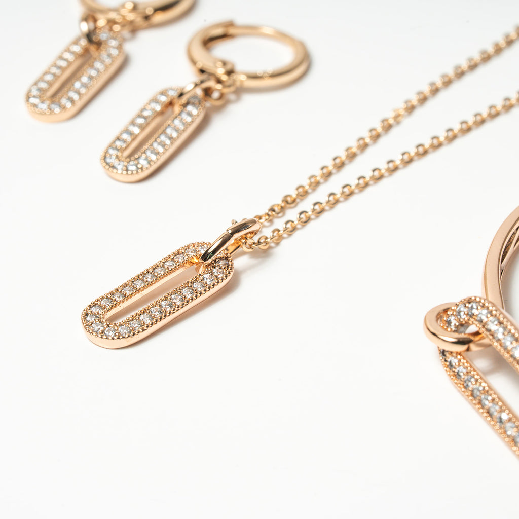 Rose gold necklace with diamond-encrusted pendants on a white background. Harma Jewelry Cubic Zirconia Incrusted Sumptuous Paper Clip Bangle Chain Necklace Earrings Set