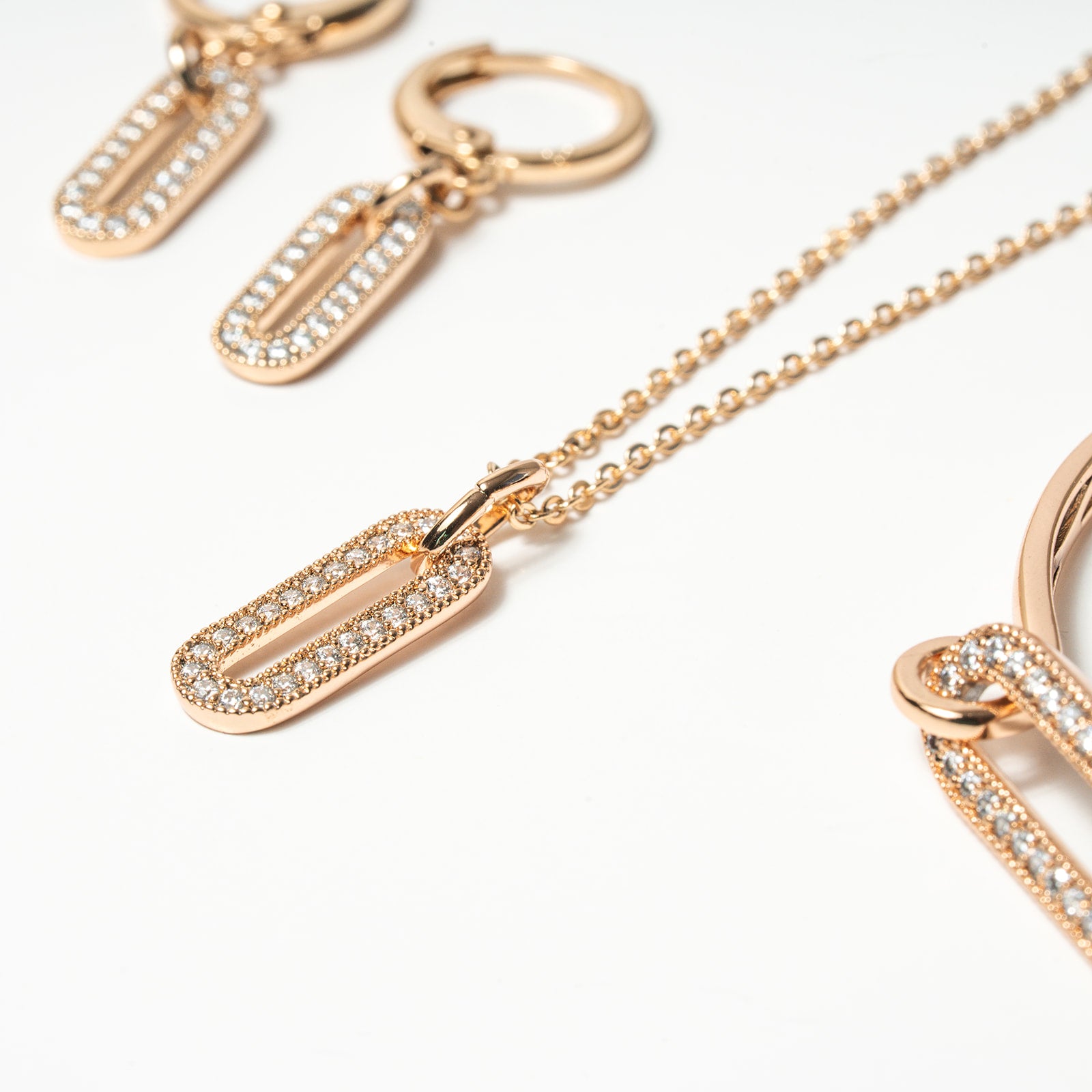 Rose gold necklace with diamond-encrusted pendants on a white background. Harma Jewelry Cubic Zirconia Incrusted Sumptuous Paper Clip Bangle Chain Necklace Earrings Set