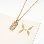 Gold necklace with a pendant on a white surface. Harma Jewelry Cubic Zirconia Incrusted Sumptuous Paper Clip Pendant Necklace Set