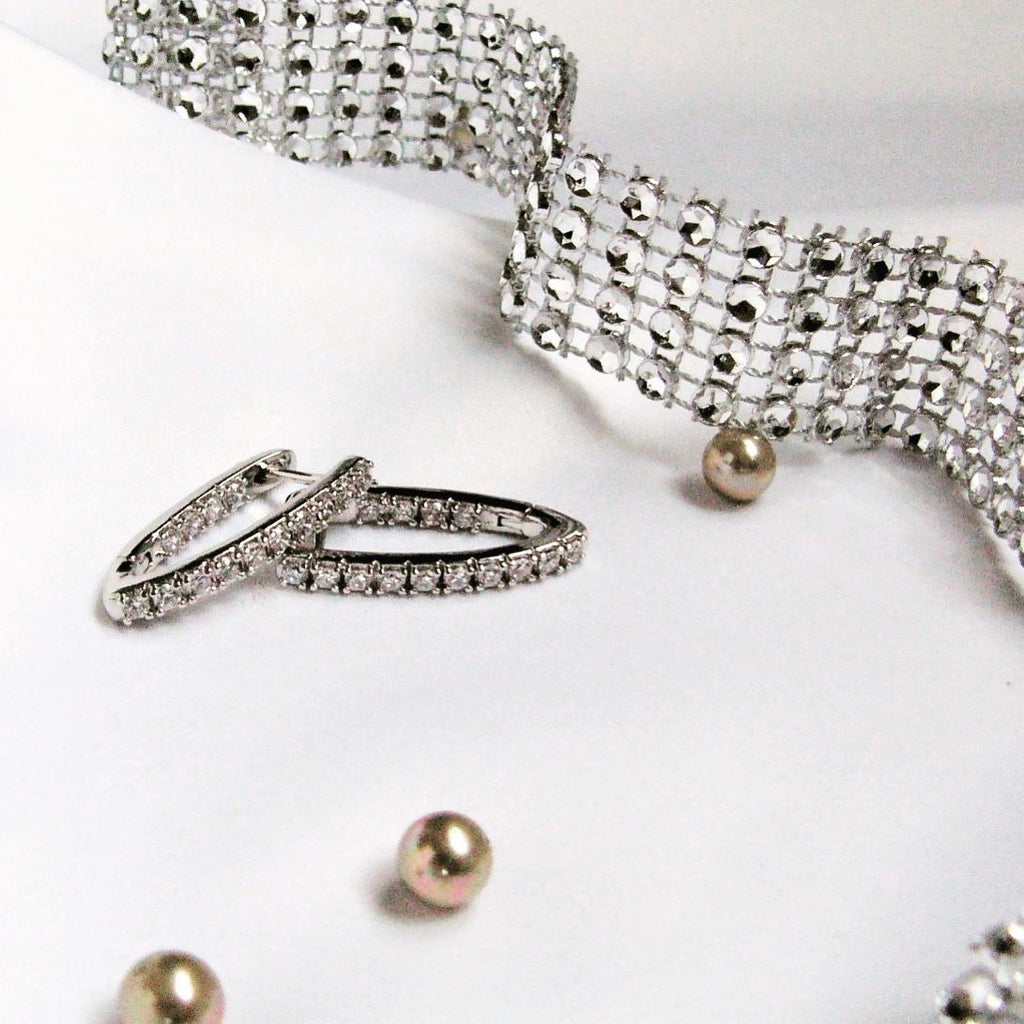 Silver bracelet, ring, and earrings on a white background Harma Jewelry Cubic Zirconia Inside out Huggie Hoop Earrings 