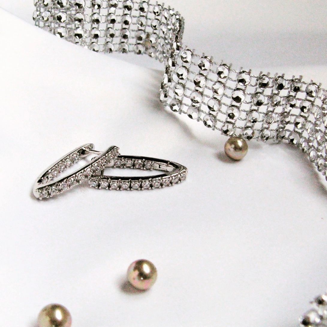 Silver bracelet, ring, and earrings on a white background Harma Jewelry Cubic Zirconia Inside out Huggie Hoop Earrings 