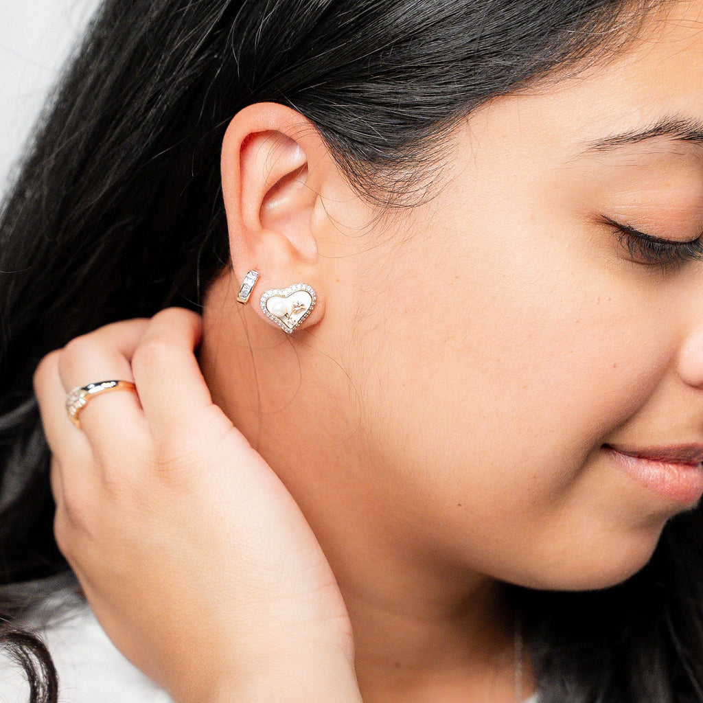 Woman wearing a gold ring and earrings, with a white lace top.