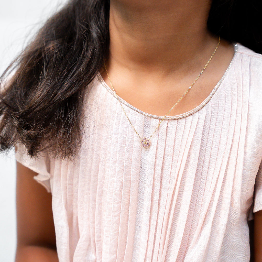 Person wearing a white pleated top with a necklace against a neutral. Harma Jewelry Gold Plated Little Bloom PINK Zirconia Necklacebackground