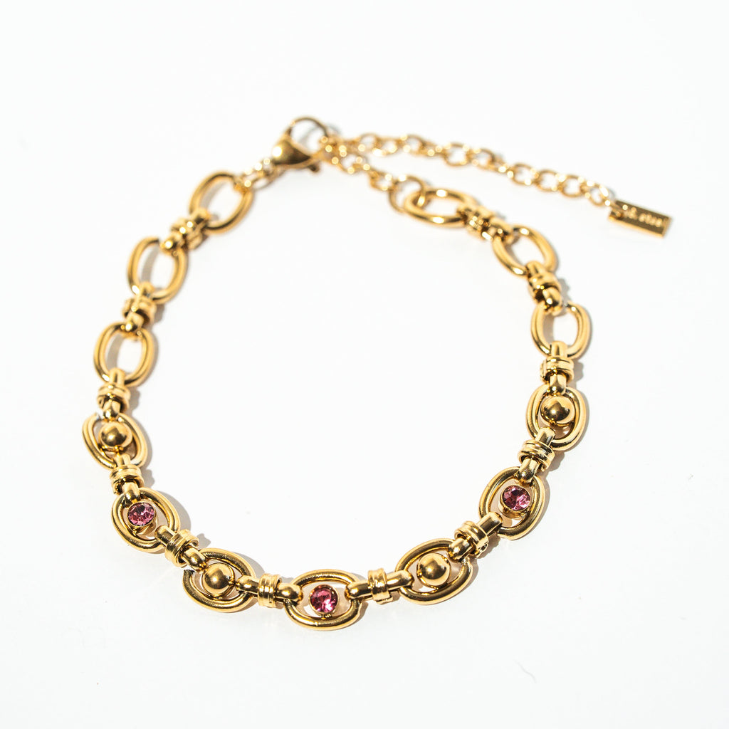 Gold bracelet with pink gemstones on a white background