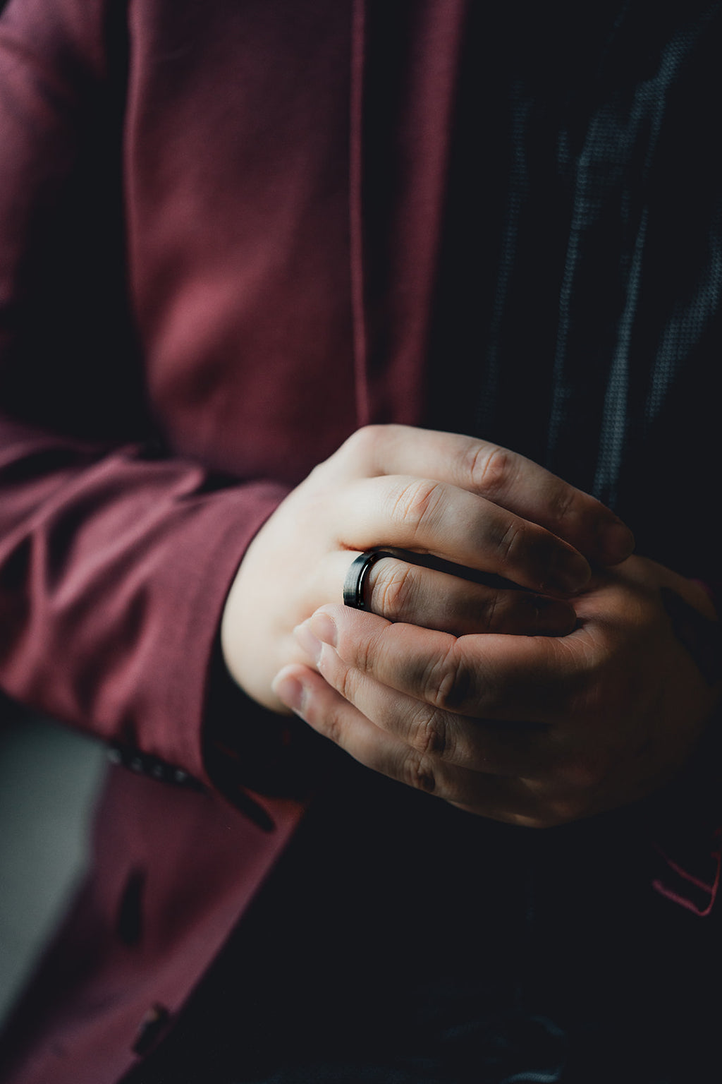 Close-up of a person's hands with a dark ring, wearing a burgundy sleeve. Harma Jewelry Men Tungsten Carbide Band Ring Black Simple 