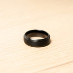 Black ring on a wooden surface. Harma Jewelry Men Tungsten Carbide Band Ring Black Silver Simple 