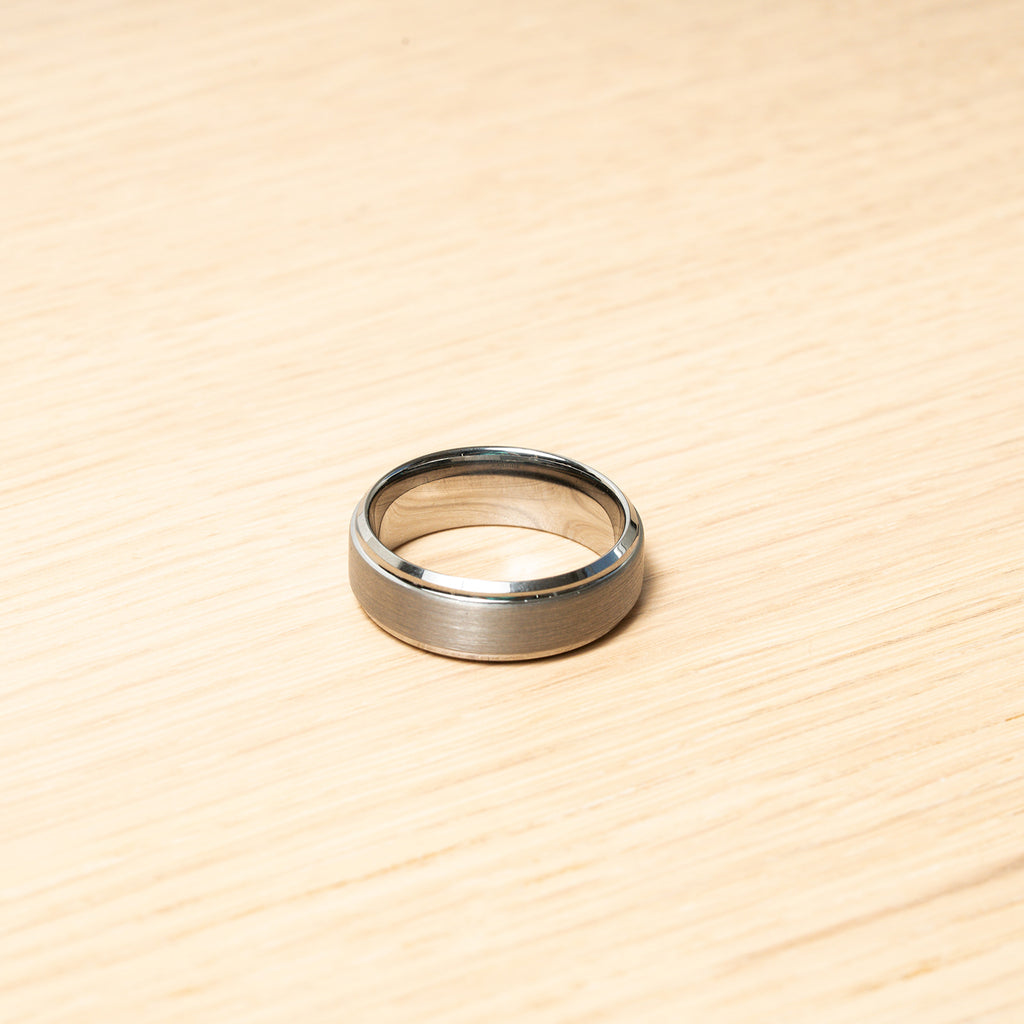 Silver ring on a wooden surface. Harma Jewelry Men Tungsten Carbide Band Ring Silver Simple 