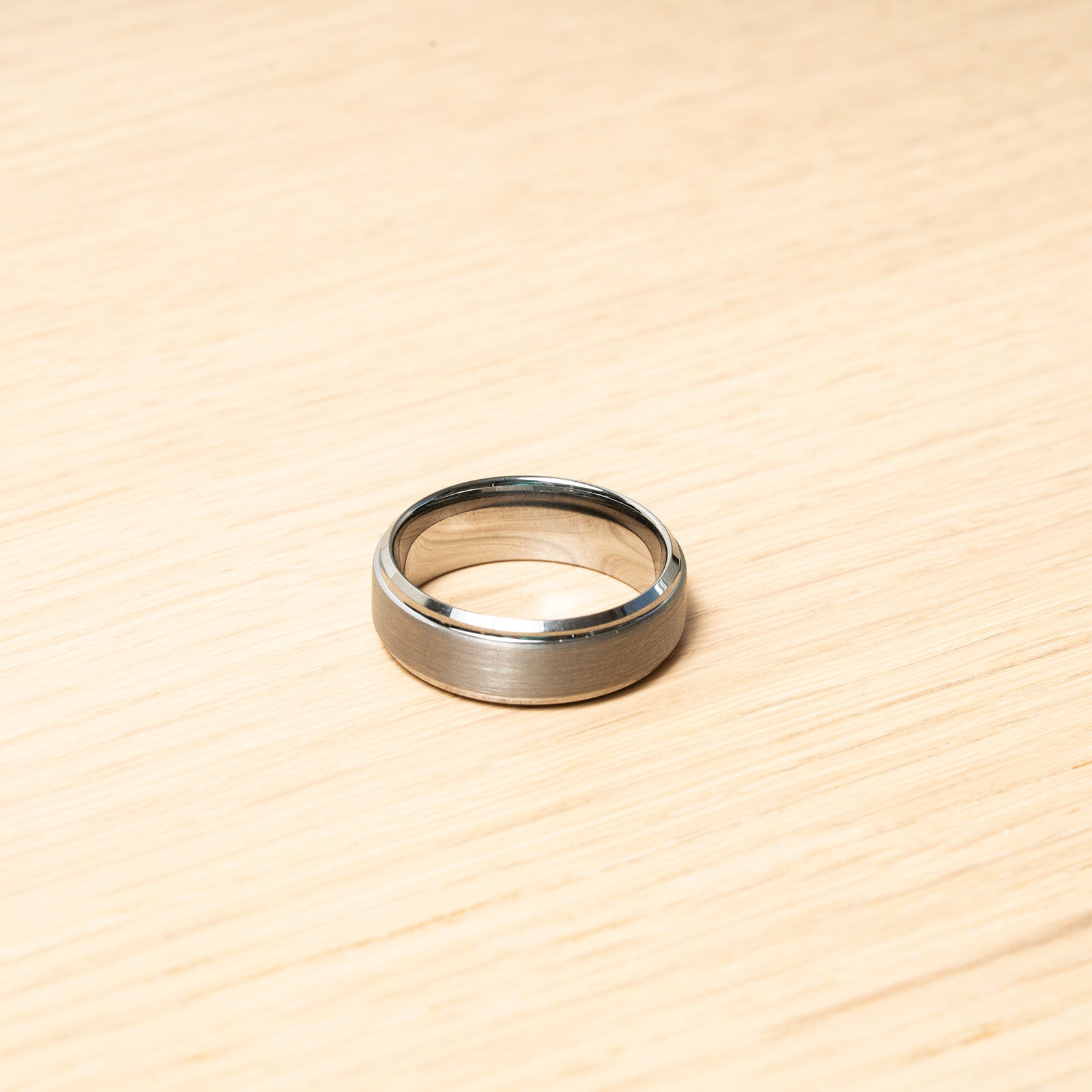 Silver ring on a wooden surface. Harma Jewelry Men Tungsten Carbide Band Ring Silver Simple 