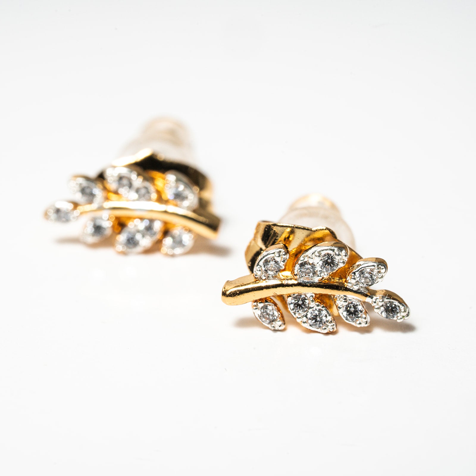 Gold and pearl leaf-shaped earrings on a white background. Harma Jewelry Olive Branch Of Hope Stud Earrings Full Cubic Zirconia Gold Plated