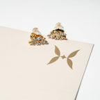 Gold and crystal earrings on a beige card with a logo. Harma Jewelry Olive Branch Of Hope Stud Earrings Full Cubic Zirconia Gold Plated