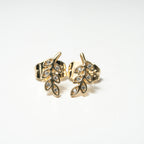 Gold leaf-shaped earrings with embedded stones on a white background