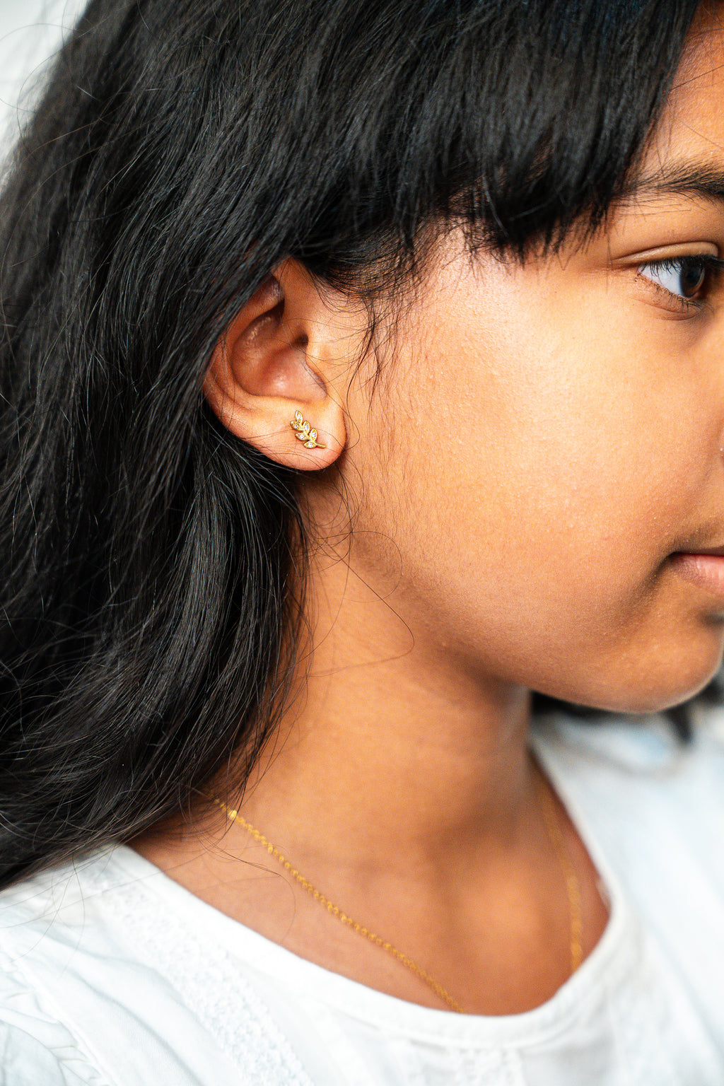 Close-up of a person wearing gold earrings and a necklace.