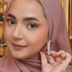 Woman wearing a pink hijab and earrings, adjusting her earring. Radiant Chandelier Marquise Dangle Earrings