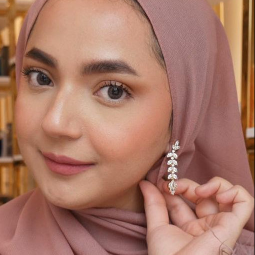 Woman wearing a pink hijab and earrings, adjusting her earring. Radiant Chandelier Marquise Dangle Earrings