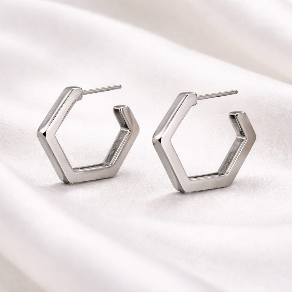 Hexagonal silver earrings on a satin surface