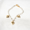 Bracelet with gold heart-shaped charms and white beads on a light background. Harma Jewelry White Pearl Gold Heart Charm Bracelet