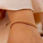 Gold bracelet on a wrist with a blurred background. Harma Jewelry gold plated Dual Radiance PINK Tennis Bracelet